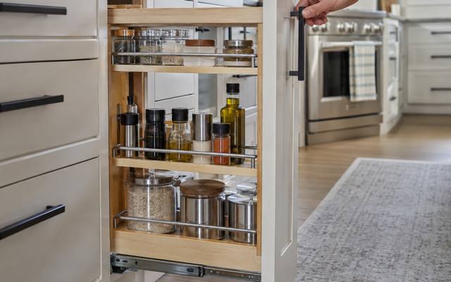 A narrow pull-out spice cabinet beside a stack of white drawers.